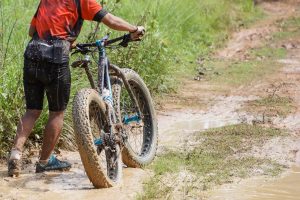 Fat bike cyclist riding on a muddy road / Cycling in wet condition concept